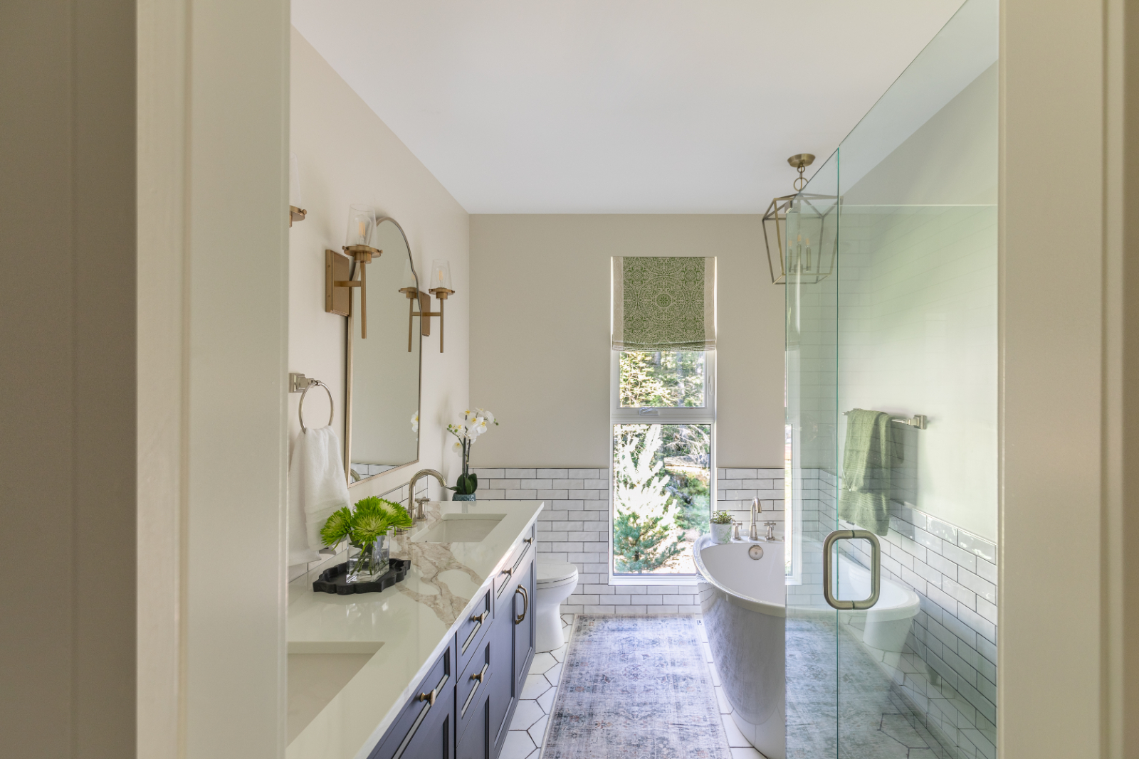 Navy vanity with gold accents, freestanding tub, and glass shower enclosure, a serene example of modern bathroom design.