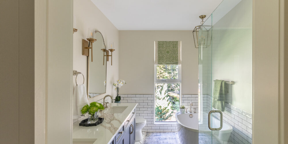 Navy vanity with gold accents, freestanding tub, and glass shower enclosure, a serene example of modern bathroom design.