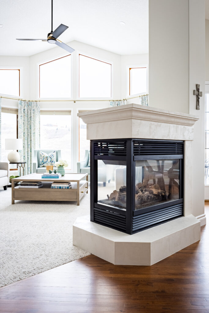 Living room with panoramic windows, central glass fireplace, and bright seating—showcasing interior design trends.