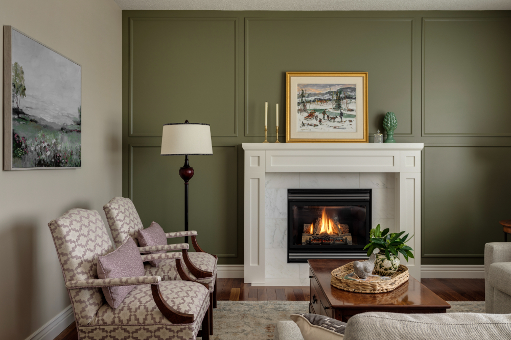 Cozy living room with green accent wall, white fireplace, patterned chairs, and wall art—classic interior design trends.
