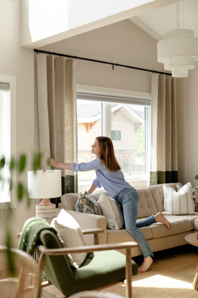 Designer styling living room curtains, adjusting window treatments to reflect current interior design trends.