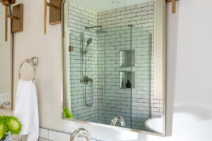 Modern shower design with a green herringbone tile feature, matte black fixtures, and glass enclosure, combining style and function.