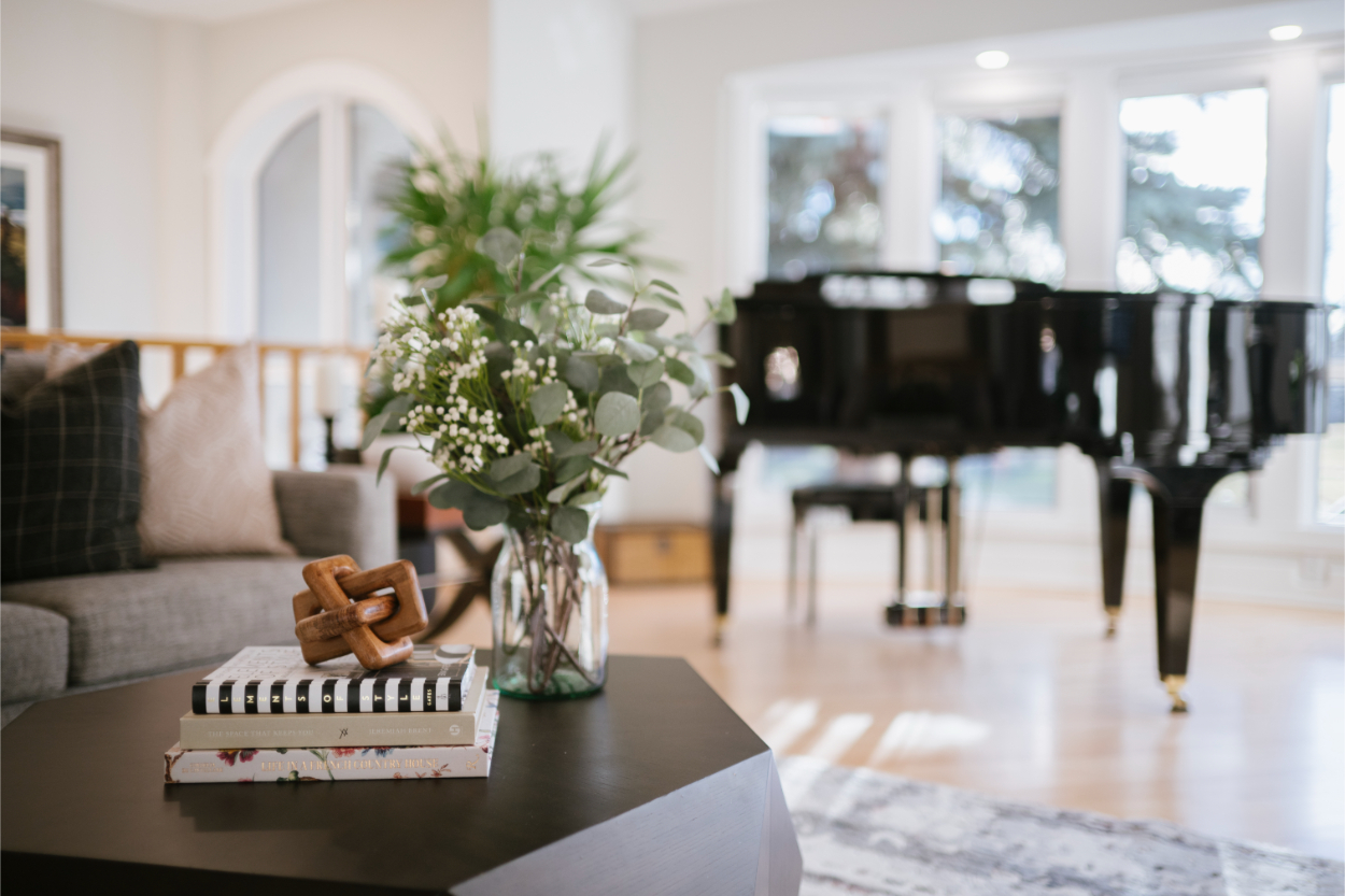 Modern living room from Varsity Estates home renovation featuring piano, greenery, and curated coffee table styling.