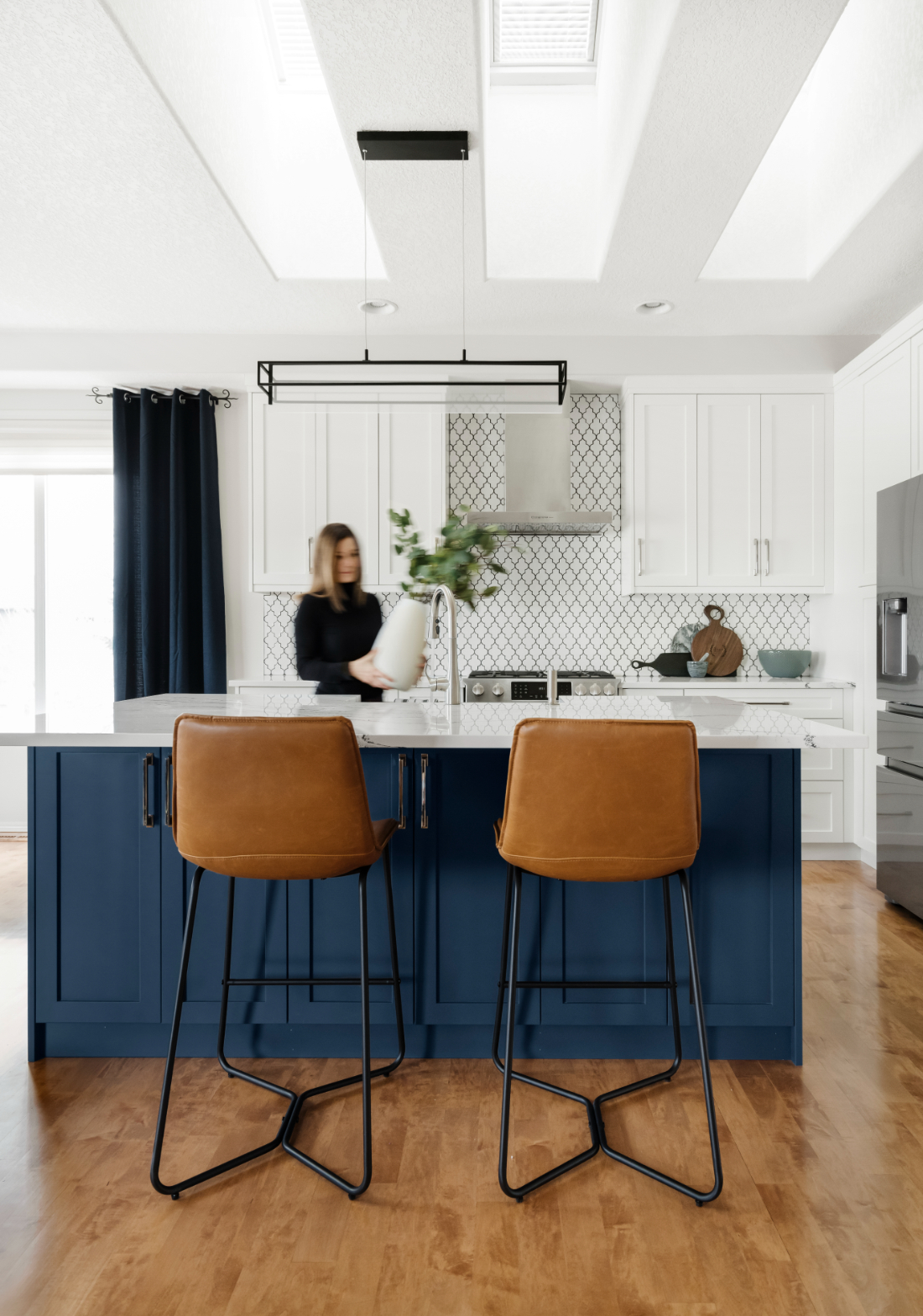 Modern kitchen featuring a bold navy island, leather stools, white shaker cabinets, and geometric backsplash. A vibrant space designed for everyday elegance | home renovation tips