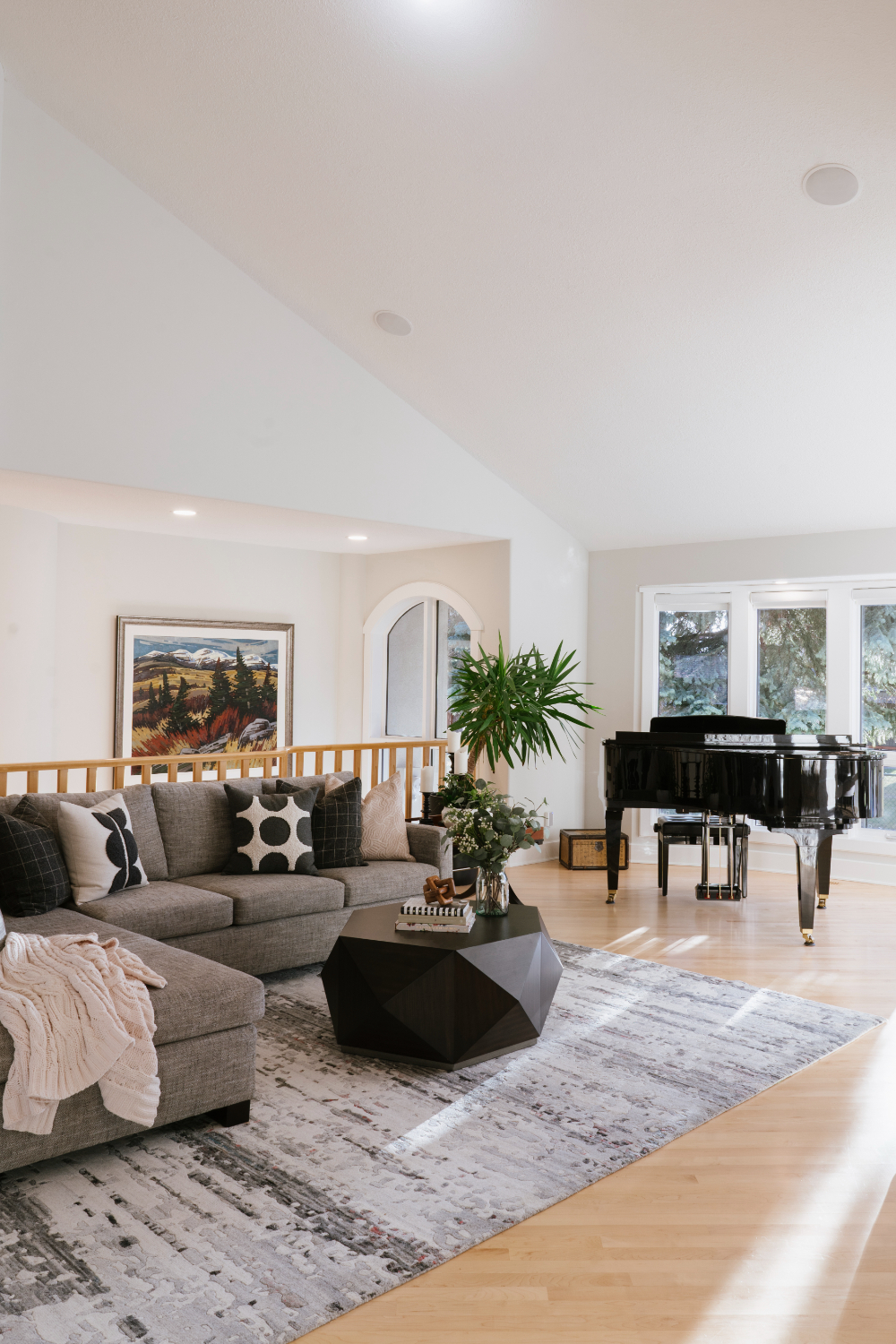 Airy living room with large windows, sectional sofa, geometric table, and grand piano, reflecting balanced styling and layout in interior decorator vs interior designer spaces.