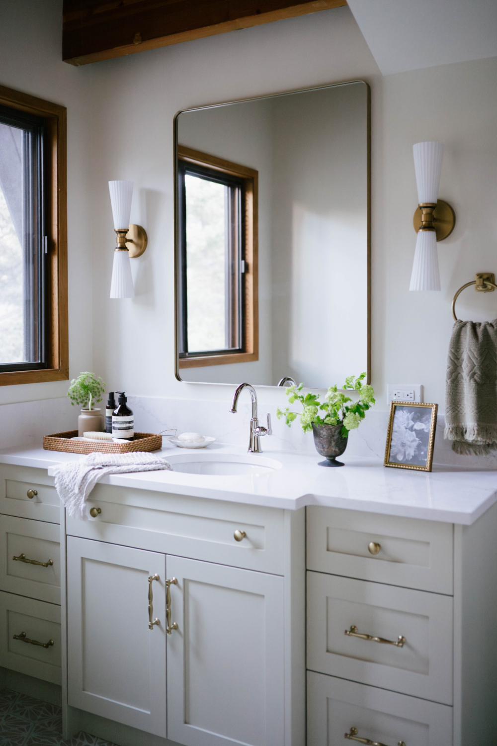 Modern bathroom vanity with brass fixtures, framed mirror, and soft decor accents, demonstrating subtle styling differences in interior decorator vs interior designer approaches.