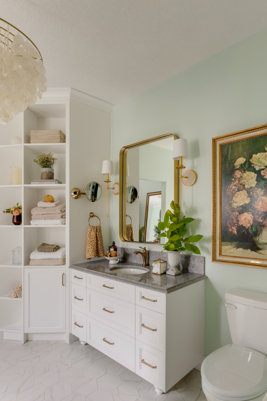 White bathroom vanity with grey stone countertop, brass fixtures, open shelving, and sage green walls designed by Room Service Interiors.