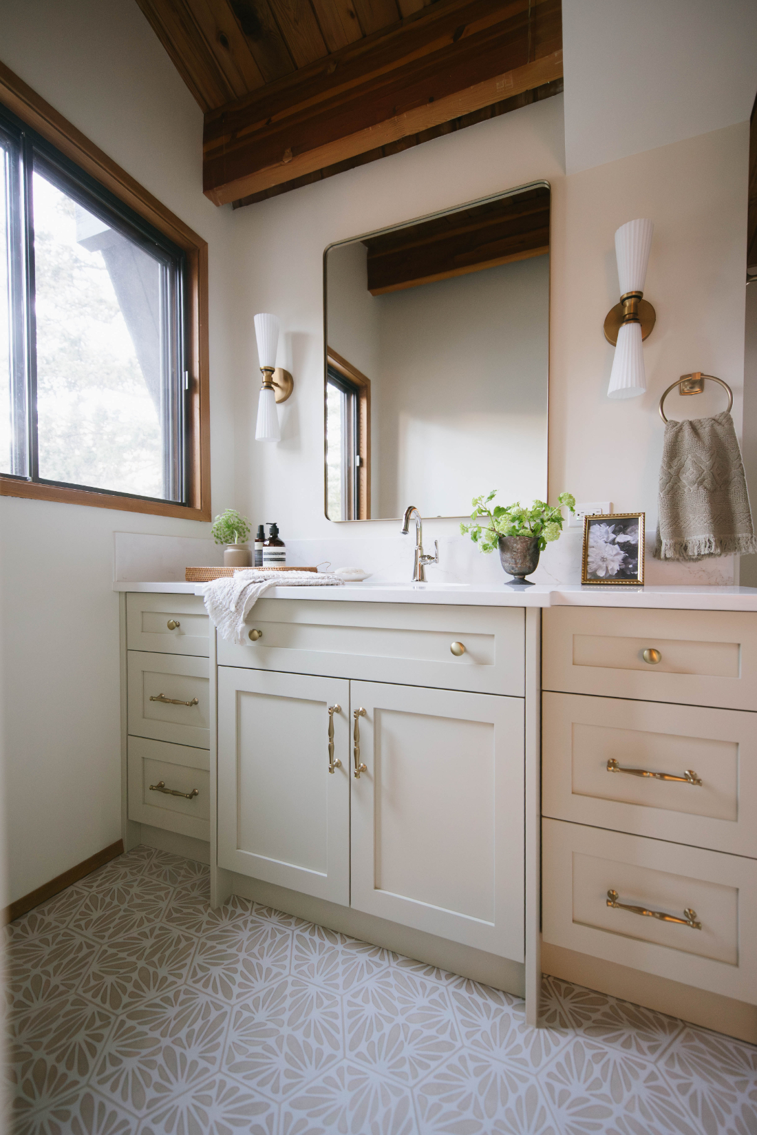 Cream shaker vanity with brass hardware, patterned tile floor, and wood beam ceiling in a Room Service Interiors bathroom renovation.