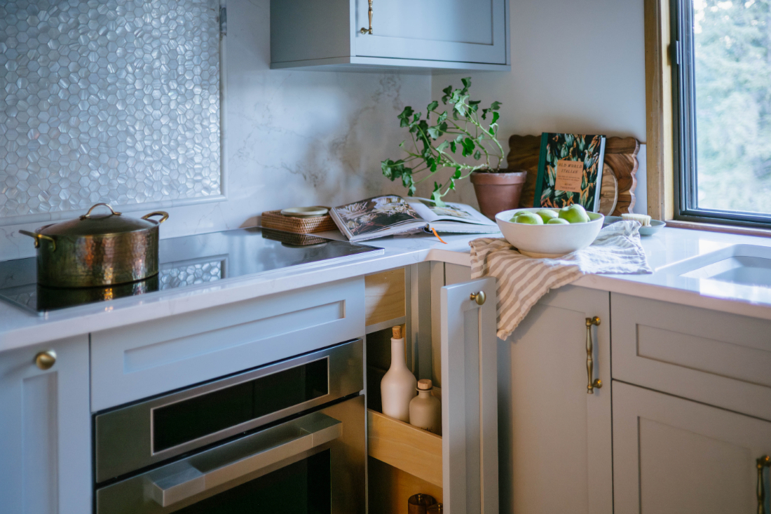 White shaker kitchen cabinets with brass pulls, hexagon tile backsplash, and open lower cabinet styling in a Calgary kitchen renovation.