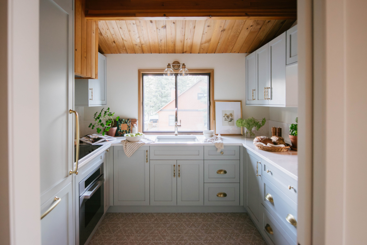 Compact kitchen design by Room Service Interiors with custom cabinetry, brass hardware, and abundant natural light. This small house interior maximizes function and visual openness through smart layout planning and streamlined storage.