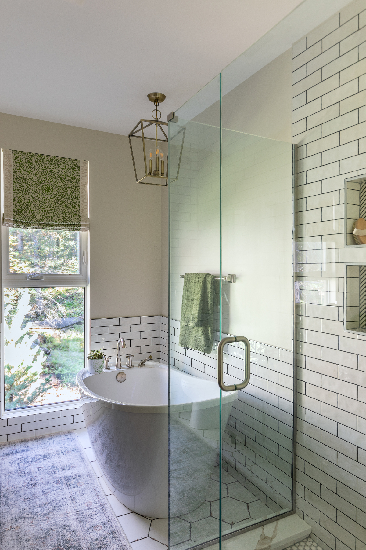 Bright bathroom renovation in Calgary featuring a freestanding tub, glass walk-in shower, white subway tile, and large window.